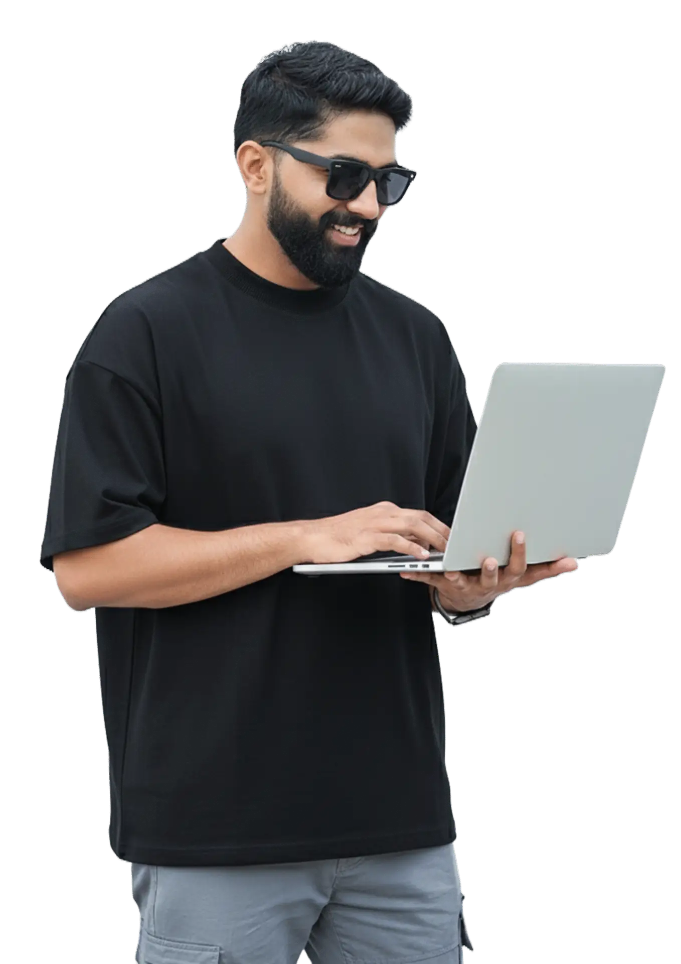 A man in a black t-shirt and sunglasses working intently on his laptop in a casual setting.